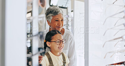 Buy stock photo Child, optometrist and picking frame in mirror, prescription glasses and helping client at store. Woman, optical shop and specialist consulting on lens for girl, excited kid and care at eye exam