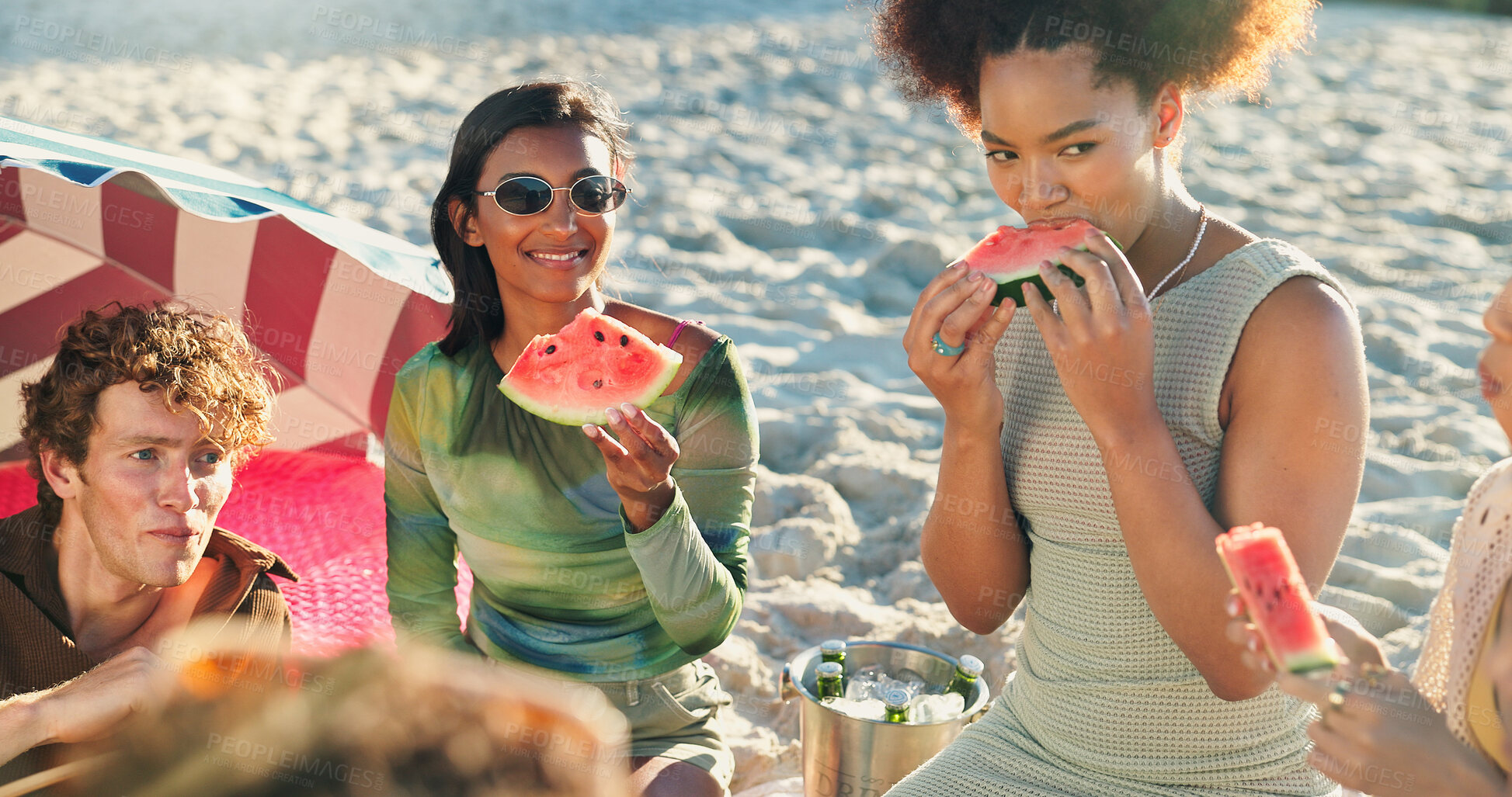 Buy stock photo People, friends and eating with watermelon at beach, picnic and conversation with reunion on vacation. Group, women and men with fruit, happy and outdoor together with diversity by ocean in sunshine