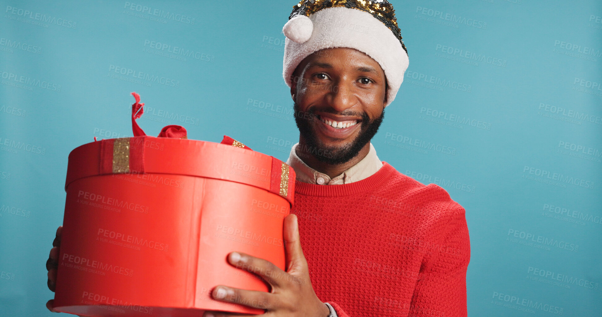 Buy stock photo Portrait, black man and box for Christmas in studio of festive celebration, surprise present and Santa Claus. Smile, male person and gift for giveaway announcement, holiday reward and blue background