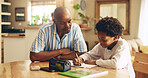 House, help and child with notebook, dad and education for boy, growth and development in kitchen. Bonding, black man and assistance for homework, writing and knowledge for exam, math and home