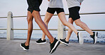 Fitness people, legs and running at ocean for exercise, wellness and cardio training with fresh air. Runner group, speed and challenge at seaside for marathon, endurance and lose weight in Spain