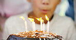 Birthday cake, celebration and blowing candles for child and flame to make a wish and enjoy surprise at home. Kids, dessert and hope at party event with food, gifts and closeup of prayer in house