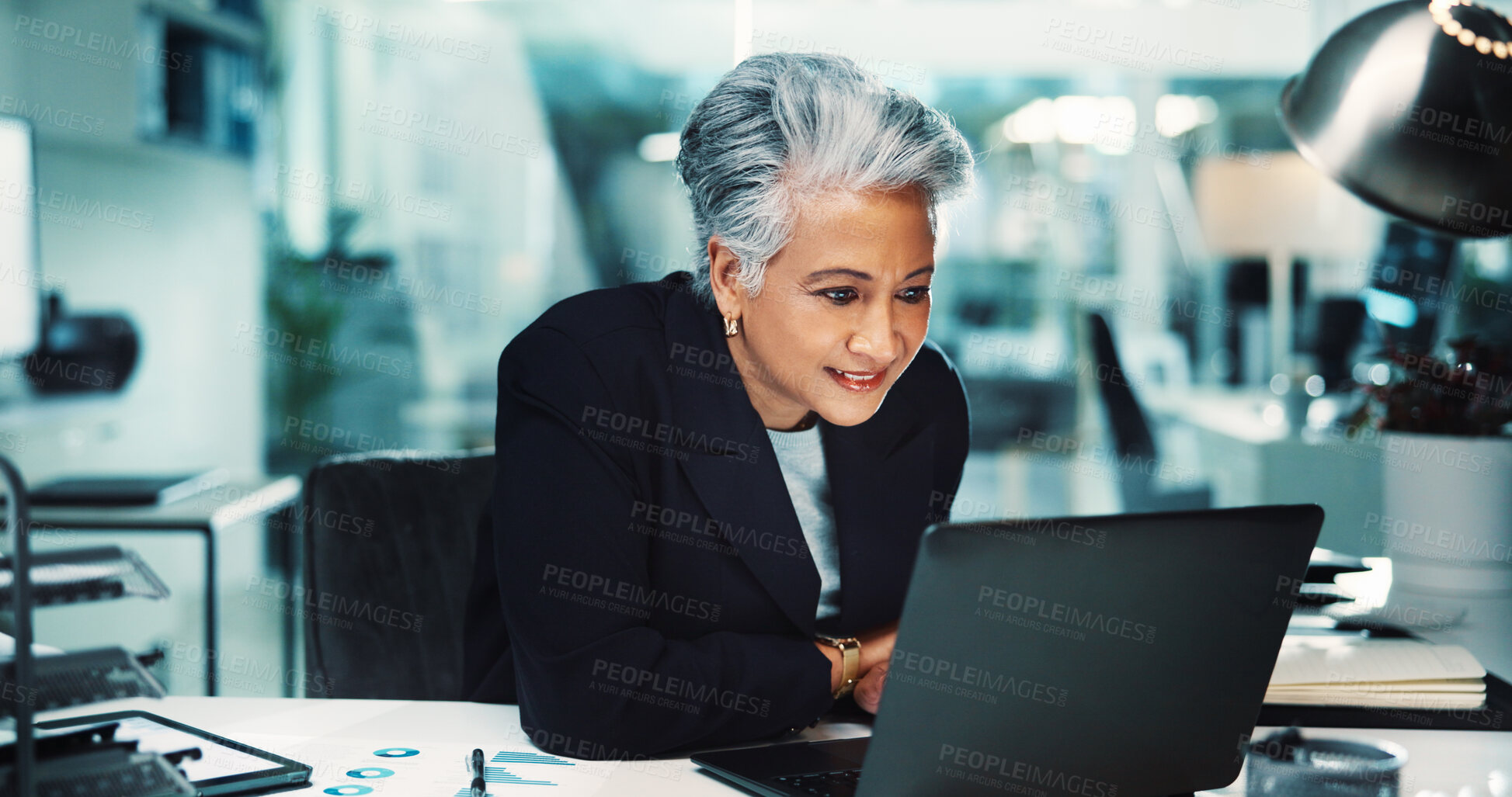 Buy stock photo Reading, accounting or mature woman on laptop for finance management, business and budget review. Accountant, night and profit report news in office for audit deadline, tax compliance and research