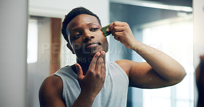Buy stock photo Black man, gua sha and face with skincare for dermatology, facial or anti aging treatment at home. African, male person and beauty tool for hygiene, cosmetics or skin routine in bathroom at house