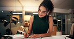 Business woman, writing and night with book for online course, virtual class or learning workshop at office desk. Female person, journalist or junior copywriter taking notes for seminar at workplace
