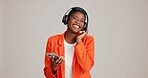 Black woman, headphones and phone for music in studio, streaming hip hop album and white background. Female person, connection and listening to radio sound, entertainment and online subscription
