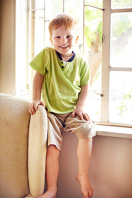 Buy stock photo Portrait, happy child and boy in home for relax, weekend and break in living room. Cute redhead, young kid and smile in house to chill by window, adorable and growth for development in New Zealand