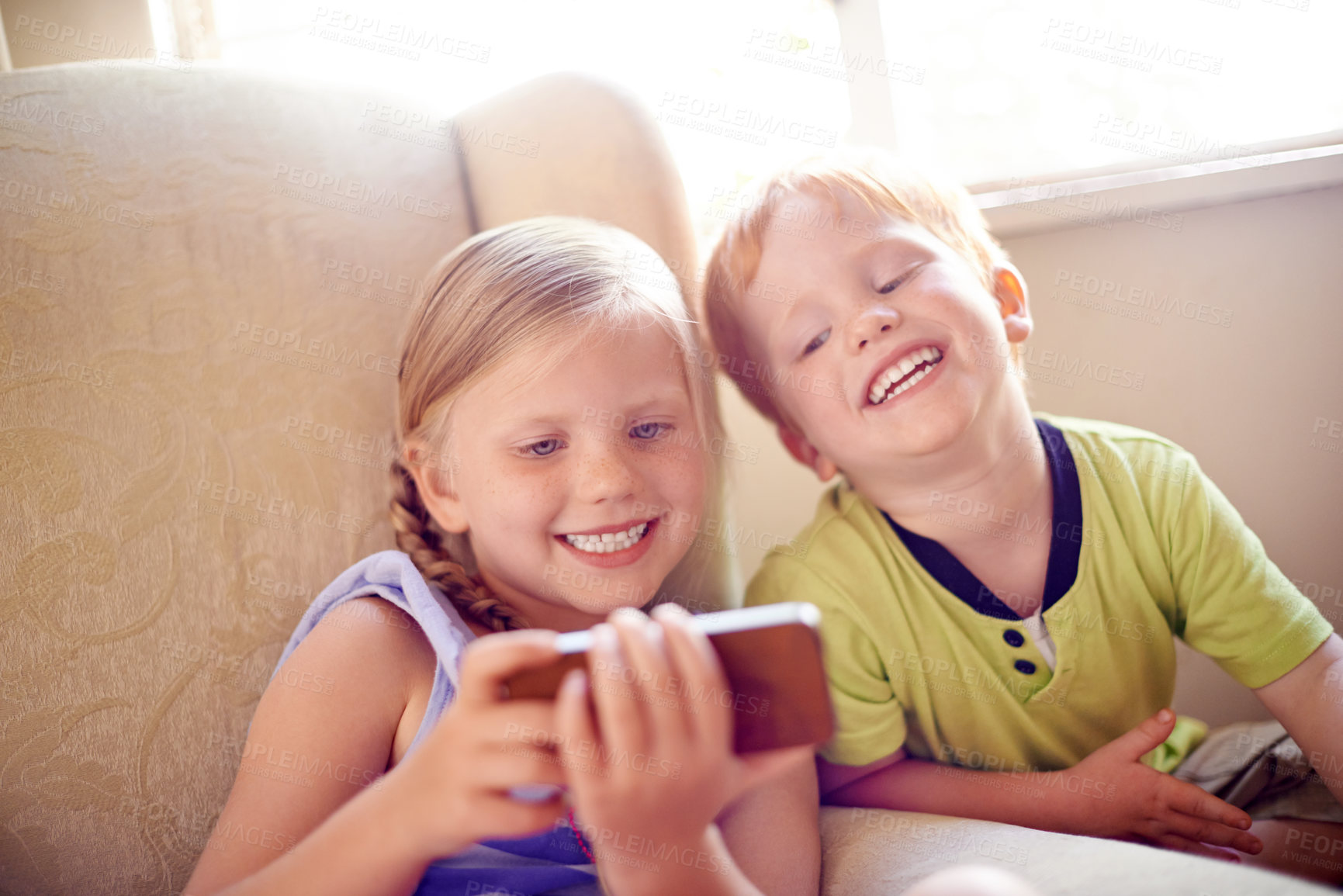 Buy stock photo Laughing, siblings and children with smartphone, watching and smile for movies in home, sofa or online. House, fun and kids with mobile for entertainment, streaming or subscription for film in lounge