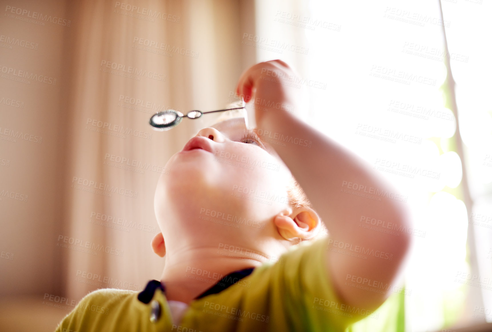 Buy stock photo Home, blowing bubbles and boy with fun, game and playful with liquid, motor skills and activity. Soap, apartment and kid with freedom, growth and youth development with child and break in lounge