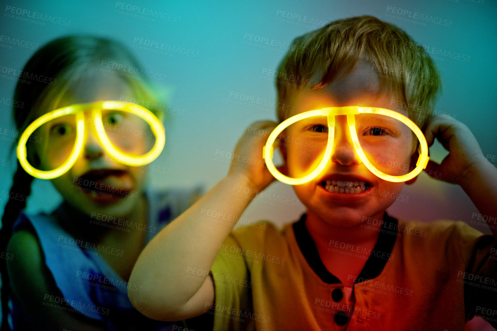 Buy stock photo Night, kids and neon glasses in home for fun, playing and crazy face for Halloween party. Children, siblings and fluorescent eyewear in dark for cyberpunk birthday theme, bonding and silly childhood