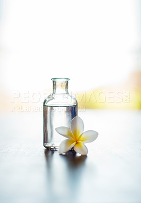 Buy stock photo Wellness, mockup and essential oil with flower on table for skin health, healthy body and aromatherapy massage. Interior space, cosmetics and healing product for skincare, antioxidants and anti aging