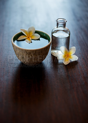 Buy stock photo Flower, spa and essential oil on table with water, natural product and bowl for fragrance. Holistic health, hospitality service and counter space for aromatherapy, self care and luxury wellness salon