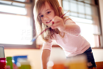 Buy stock photo Child, smile and paintbrush in home for creativity, painting and learning with colors. Young girl, playful and brush in living room for artwork, creative outlet and coordination skill development