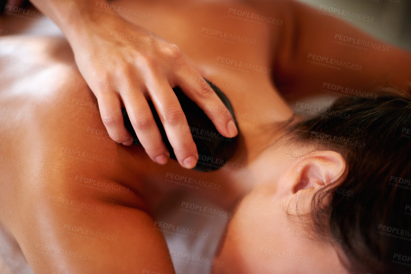 Buy stock photo Hands, spa and hot stone massage for back, muscle recovery and stress relief on holiday at resort. Person, masseuse and service with rock for circulation, relax and healing tissue at luxury lodge