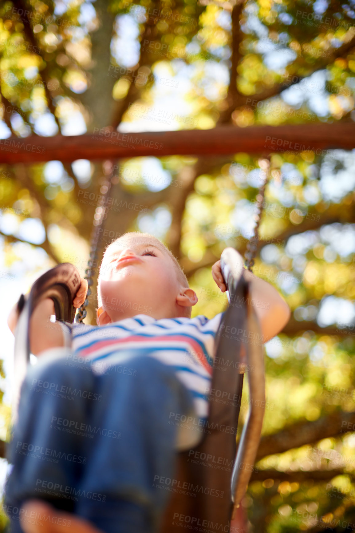 Buy stock photo Tyre, swing and kid in park with trees, outdoor adventure play and child development in nature. Relax, fun and playful boy in playground for growth, games or summer childhood on weekend from below