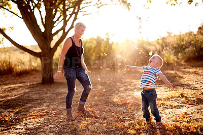 Buy stock photo Excited, leaves and mom with child in nature for playing games, bonding and have fun together. Family, park and mother with kid happy for season change, autumn and fall for childhood adventure