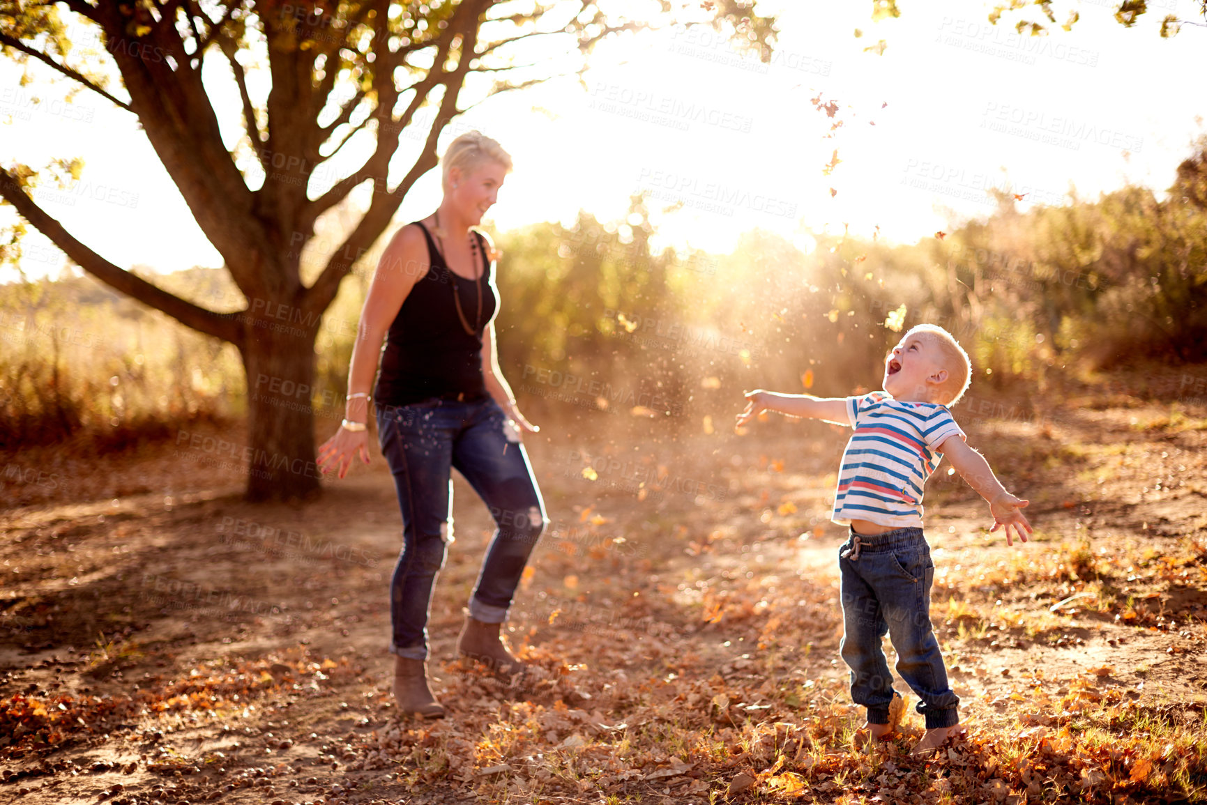 Buy stock photo Excited, leaves and mom with child in nature for playing games, bonding and have fun together. Family, park and mother with kid happy for season change, autumn and fall for childhood adventure