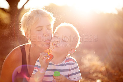 Buy stock photo Happy, blowing bubbles and child in nature with mom for fun game, childhood and bonding together outdoors. Family, sunlight and mom with young boy with soap, toys and activity for playing in park