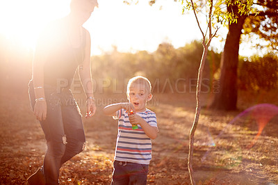 Buy stock photo Happy, blowing bubbles and child with mom in nature for fun, childhood and bonding together outdoors. Family, sunlight and boy with soap, toys and activity for playing, adventure or game in park