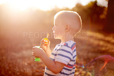 Buy stock photo Boy, kid and blowing bubbles at sunset, park and outdoor in profile with smile, memory and playful in summer. Child, toys and happy with soap, liquid and foam for games on adventure in Australia