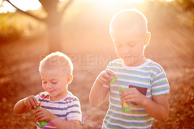 Buy stock photo Sunshine, blowing bubbles and children in nature for fun, childhood and bonding together outdoors. Family, happy and young brothers with soap, toys and activity for playing, adventure or game in park