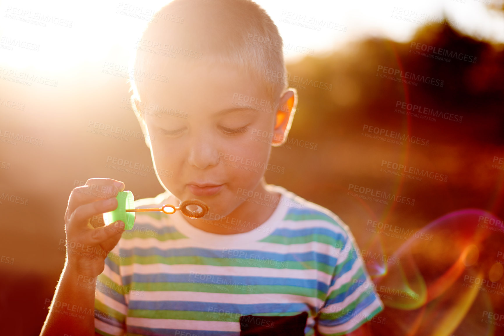Buy stock photo Bubbles, face and boy in field with fun, sunset adventure and outdoor development for kids in park. Relax, blowing and child in garden playground with soap wand, childhood games or play activity