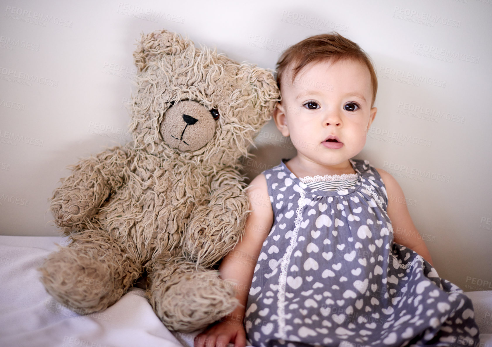 Buy stock photo Baby, girl and bed with teddy bear for playful childhood, youth or growth in development at home. Little kid, infant or adorable child with cute dress or big stuffy in bedroom for nursery at house