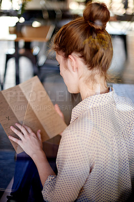 Buy stock photo Coffee shop, woman and reading with menu, food decision or beverage choice. Girl, back and lunch with options of restaurant for hunger, snack or meal at cafe or bistro for hungry customer order