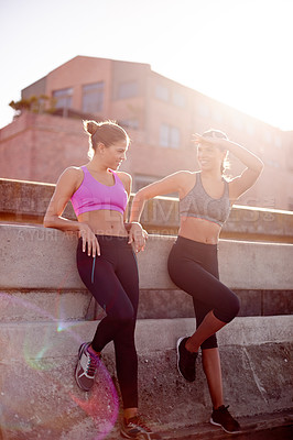 Buy stock photo Women, fitness and twins with rest in street for chat, training and smile on urban bridge in summer. People, sisters and runner on break in city for conversation, workout and partnership in Spain