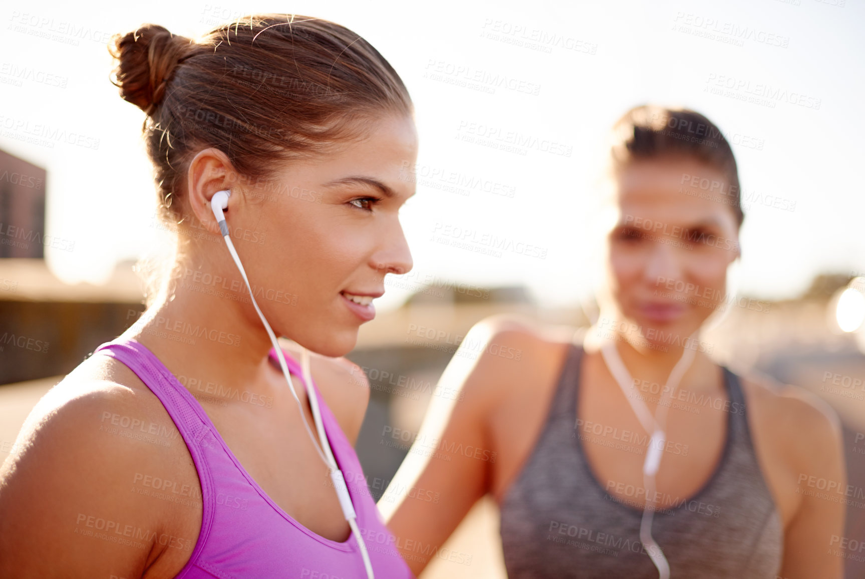 Buy stock photo Women, fitness and together with earphones in city for music, training and sisters in summer. People, runner and twins with streaming, subscription and happy for workout on urban bridge in Italy