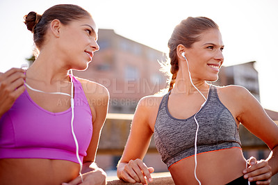 Buy stock photo Shot of twin sisters enjoying a running workout in the city