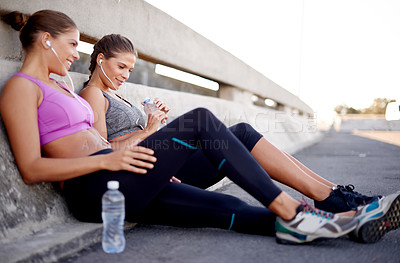 Buy stock photo Happy women, fitness and listening with earphones for break, rest or music on city bridge. Active, female people or sisters with smile for audio streaming, recovery or energy on road in an urban town