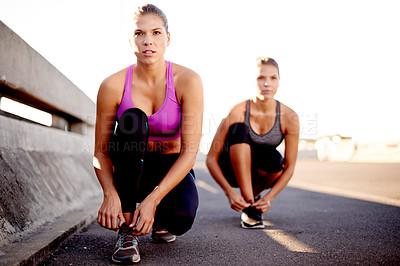 Buy stock photo Serious women, fitness or tying with shoes on bridge for workout preparation, exercise or outdoor training. Active, female people or friends getting ready with sneakers for running or sprint in city