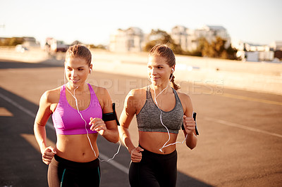 Buy stock photo Women, exercise and outdoor for running in city, streaming song and team support with fitness. Urban town, workout together and podcast for cardio sports, marathon training and earphones for twins