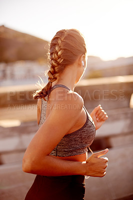 Buy stock photo Fitness, woman and running in city with music for cardio workout, endurance challenge and listening to radio. Back, wellness or girl with earphones for training jog, sport podcast or healthy exercise