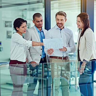 Buy stock photo Shot of a group of coworkers talking over some paperwork in an office