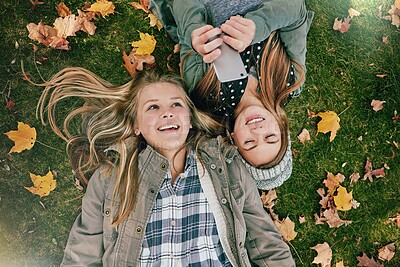 Buy stock photo High angle shot of two happy teenagers relaxing together on the grass outside