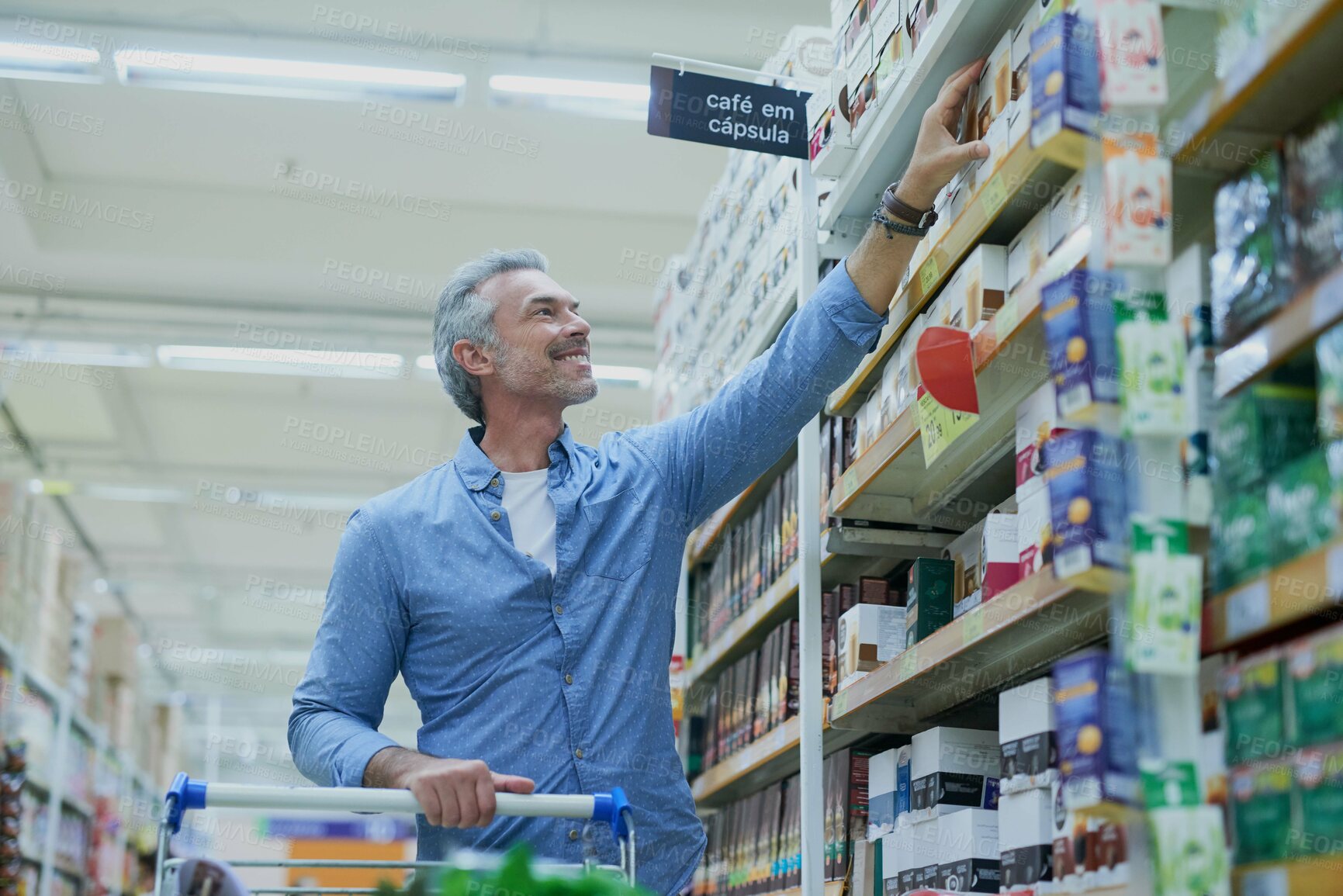 Buy stock photo Happy, shopping and man in supermarket with shelf for food, grocery and products at convenience store. Retail, consumer and person with trolley in aisle for choice, options and discount purchase