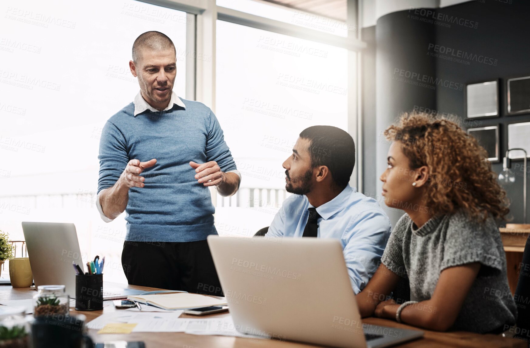Buy stock photo Businessman, laptop and coaching with team in presentation for company mission or meeting at office. Young group of employees listening to speaker on computer for training or project at workplace