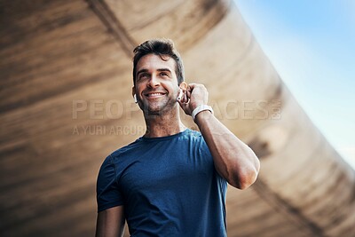 Buy stock photo Fitness, man and listening to music in city for exercise, training and healthy body workout. Sport, smile and person on earphones for radio, sound or streaming audio for wellness in low angle outdoor