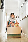 Happy mother pushing son in cardboard box enjoying their new home.Little boy having fun riding in carton box.  Encouraging pretend play