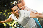 Cheerful father carrying daughter on his back. Little girl and daddy playing airplane. Child pretending to fly while getting piggyback ride at the park