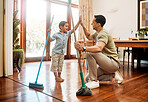 Little caucasian boy helping his father sweep and mop wooden floors for household chores at home. Happy father and son doing spring cleaning together. Kid and parent high fiving while doing tasks