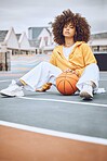 Basketball, court and sport woman portrait while sitting with ball. Stylish, edgy and afro lady looks cool in athletic clothes. Casual female model for athlete leisure and fashion clothing campaign.