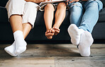 Closeup of a family sitting on a sofa using a tablet in the lounge at home. Family feet relaxing while sitting on a couch during the day