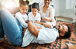 Closeup of a young hispanic family playing together on the lounge floor at home. Mixed race father and mother having fun while playing with their cute little son and daughter in the lounge at home