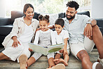 Mixed race family reading a book together on the floor at home. Hispanic mother and father teaching their little son and daughter how to read. Brother and sister learning to read with their parents