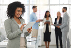 Young happy mixed race businesswoman working on a digital tablet in an office. One joyful hispanic female boss with a curly afro holding and using social media on a digital tablet at work