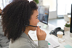 Young cheerful mixed race female call center agent answering calls while wearing a headset at work. Hispanic businesswoman with a curly afro talking on a call at a desk in an office