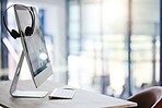 Closeup of headset hanging on a computer desktop monitor in an empty call centre office. Operating helpdesk for customer service and sales support. Telemarketing agents providing online assistance